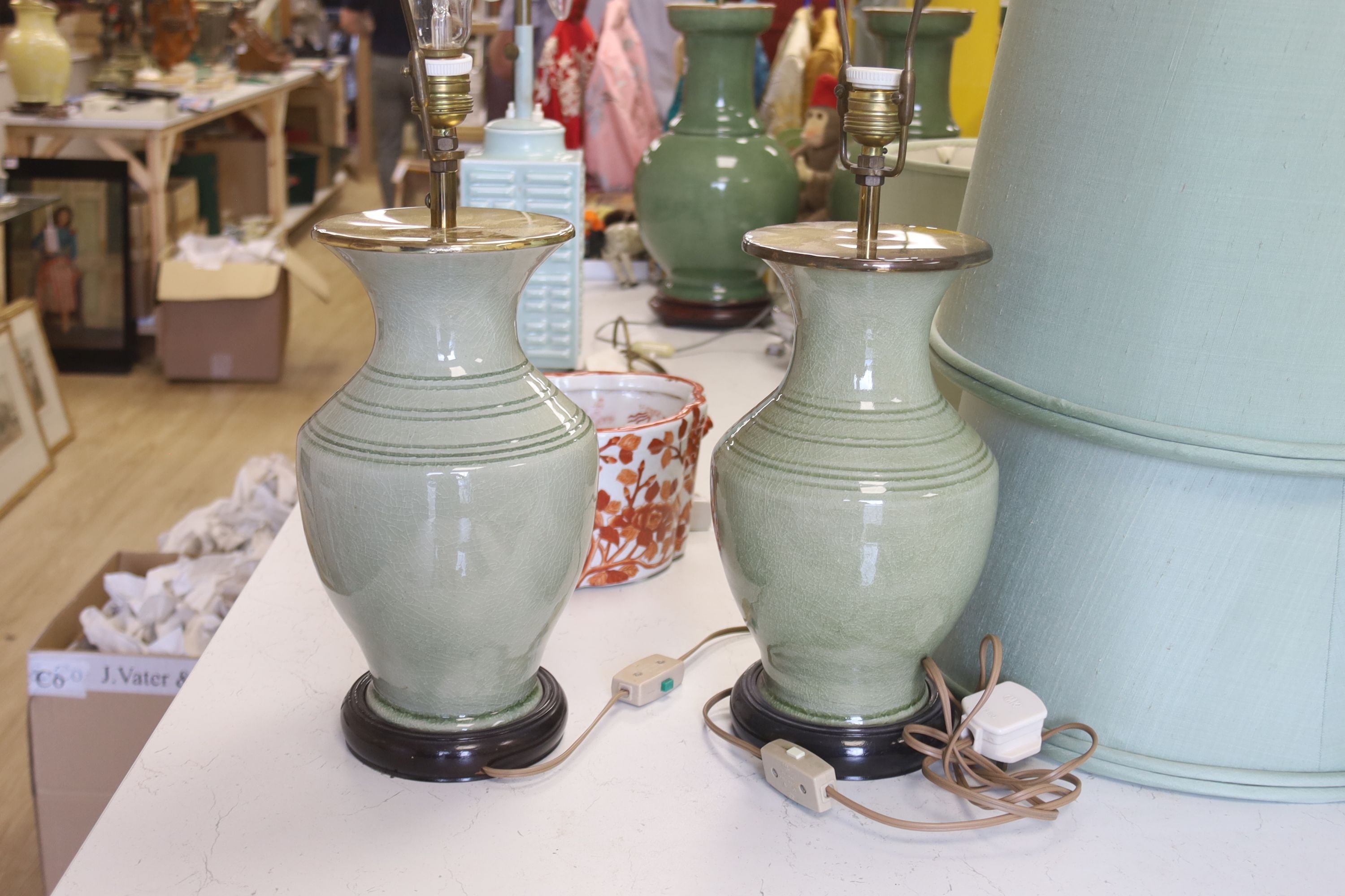 A pair of Chinese celadon glazed table lamps with green silk shades, height 33cm excluding light fitting